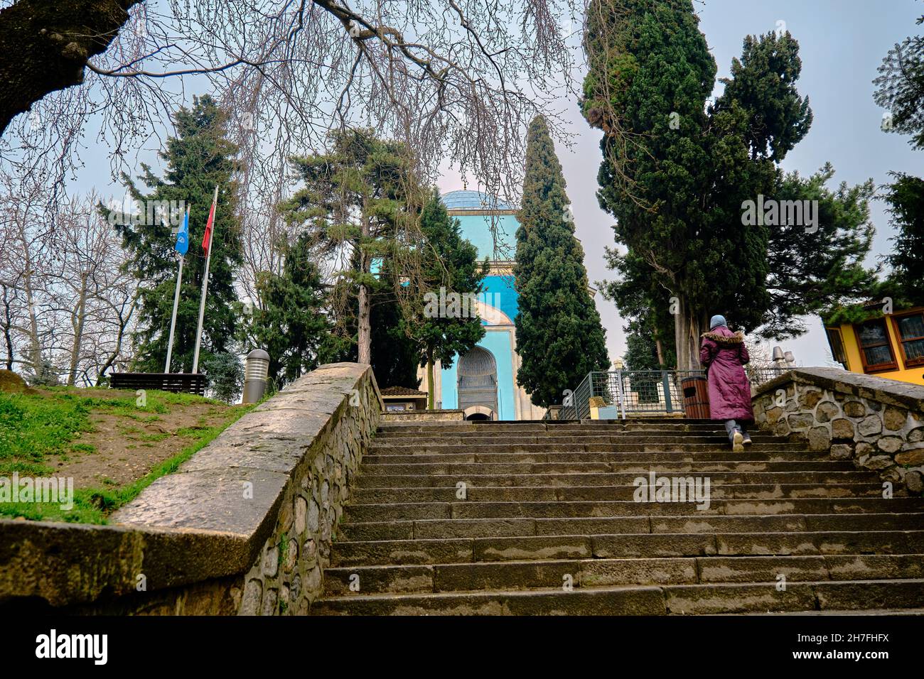 Grünes Grab (Yesil Turbe) mit Iznik-Töpferei (cini) oder Kacheln bedeckte Grabwand und wandelige Frauen mit islamischer Kleidung bei Regen. Stockfoto