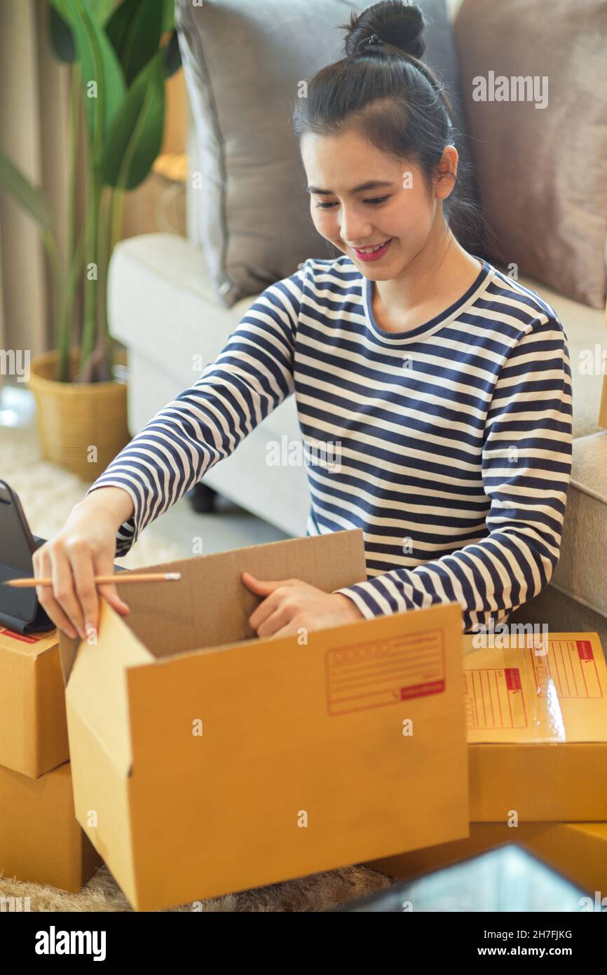 Porträt einer Gründerin eines kleinen Unternehmens, die ein Paket verpackt, um die Lieferung an ihren Kunden zu senden. KMU-Geschäftskonzept. Stockfoto