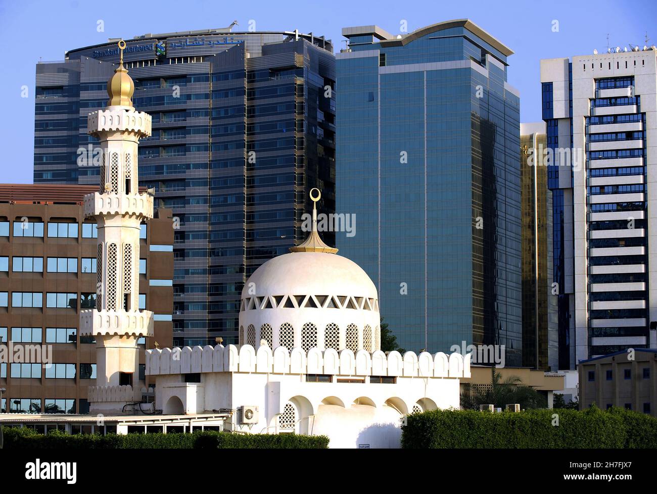 KONTRAST ZWISCHEN DER MODERNEN ARCHITEKTUR DER WOLKENKRATZER UND DER TRADITIONELLEN NAHÖSTLICHEN ARCHITEKTUR EINER MOSCHEE, ABU DHABI, DER HAUPTSTADT DER UNI Stockfoto