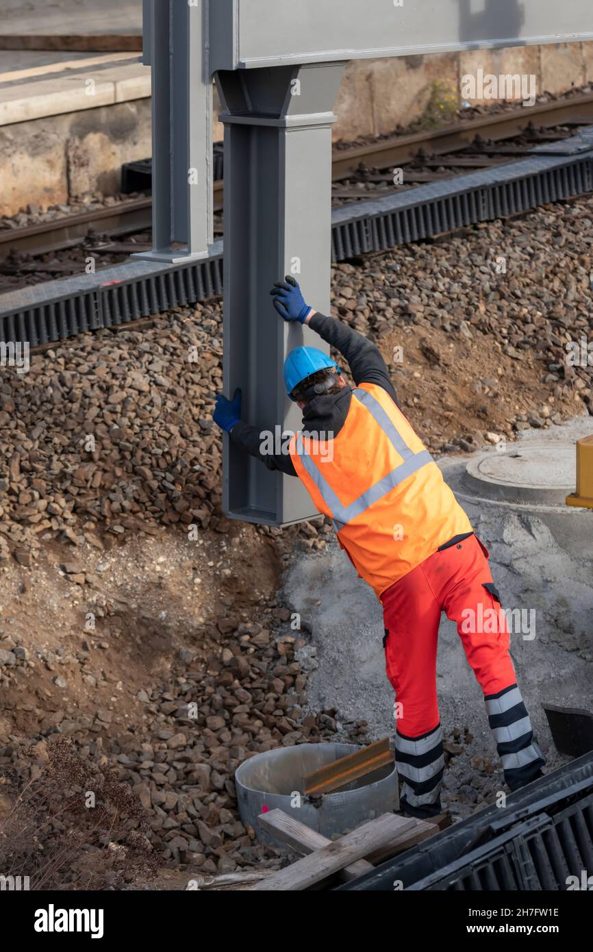 Ein Arbeiter richtet ein großes Stahlteil aus, bevor es abgesenkt wird Stockfoto