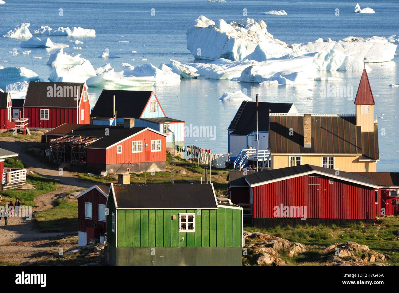 DÄNEMARK. GRÖNLAND. WESTKÜSTE. HALBINSEL NUGSSUAQ. EINIGE HÄUSER DES DORFES SAQQAQ MIT EISBERGEN. Stockfoto