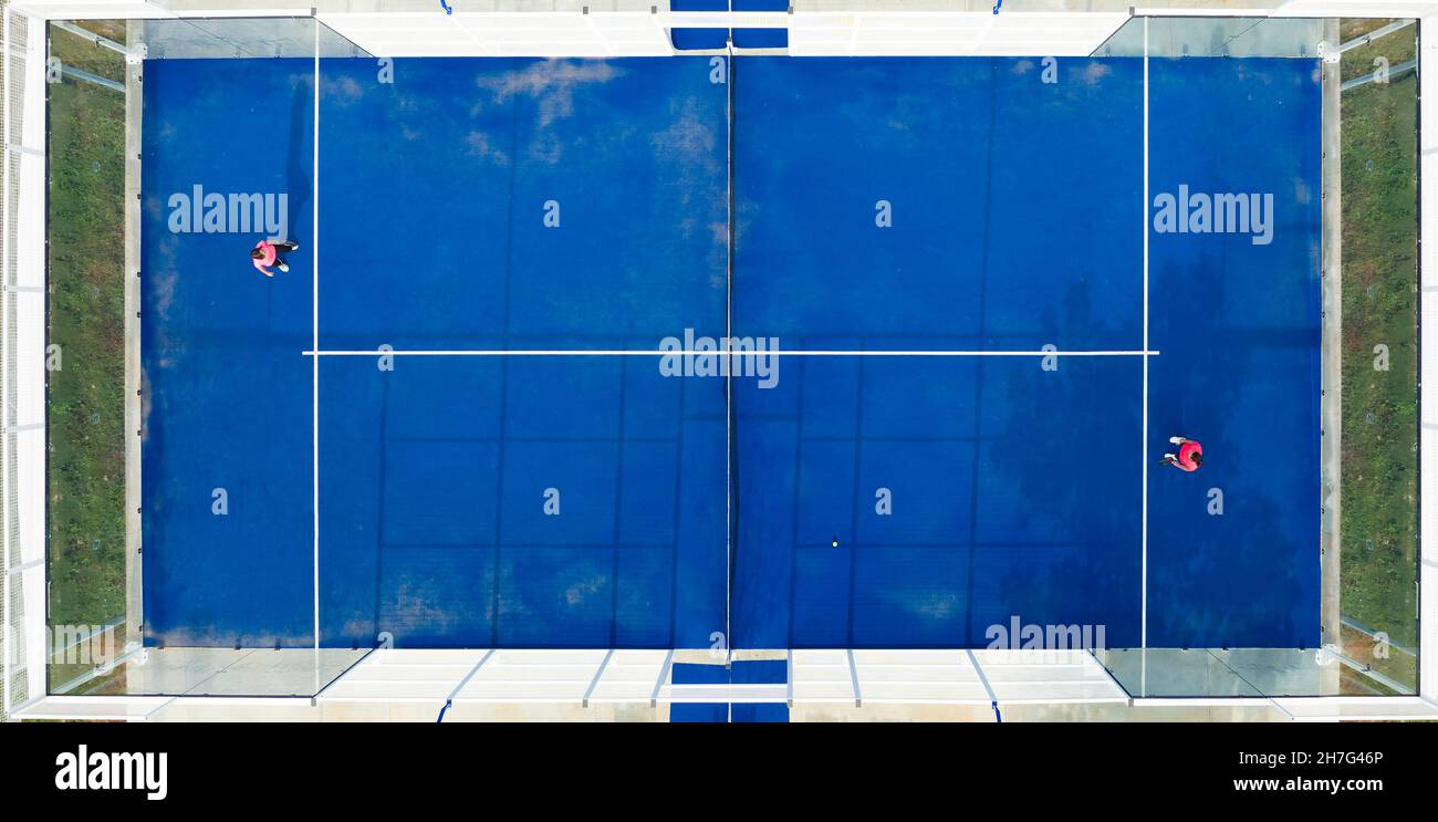 Blick von oben, atemberaubende Luftaufnahme von zwei Personen, die auf einem blauen Padel-Platz spielen. Padel ist eine Mischung aus Tennis und Squash. Es wird in der Regel in do gespielt Stockfoto