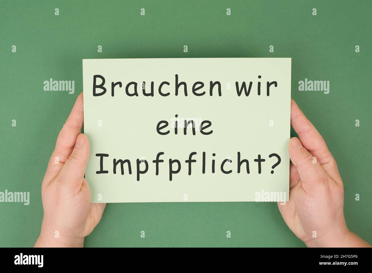 Brauchen wir eine obligatorische Impfung steht in deutscher Sprache auf dem Papier, grüner Hintergrund, covid-19 Stockfoto