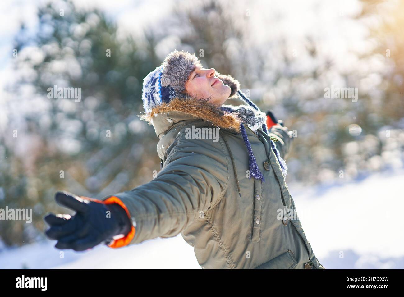 Junger, hübscher Mann, der sich in der Winterlandschaft in Wäldern amüsieren kann Stockfoto