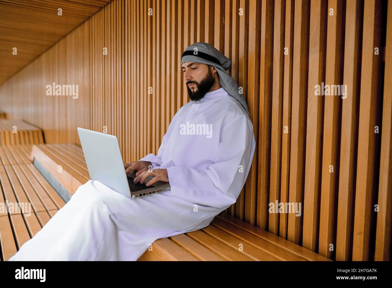 Junger arabischer Geschäftsmann, der an einem Laptop arbeitet und dabei aussieht Stockfoto