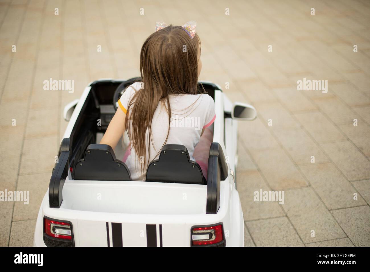 Ein Kind in einem Kinderwagen. Ein Mädchen in einem Elektroauto. Vergnügungspark. Das Mädchen fährt den Transport. Stockfoto