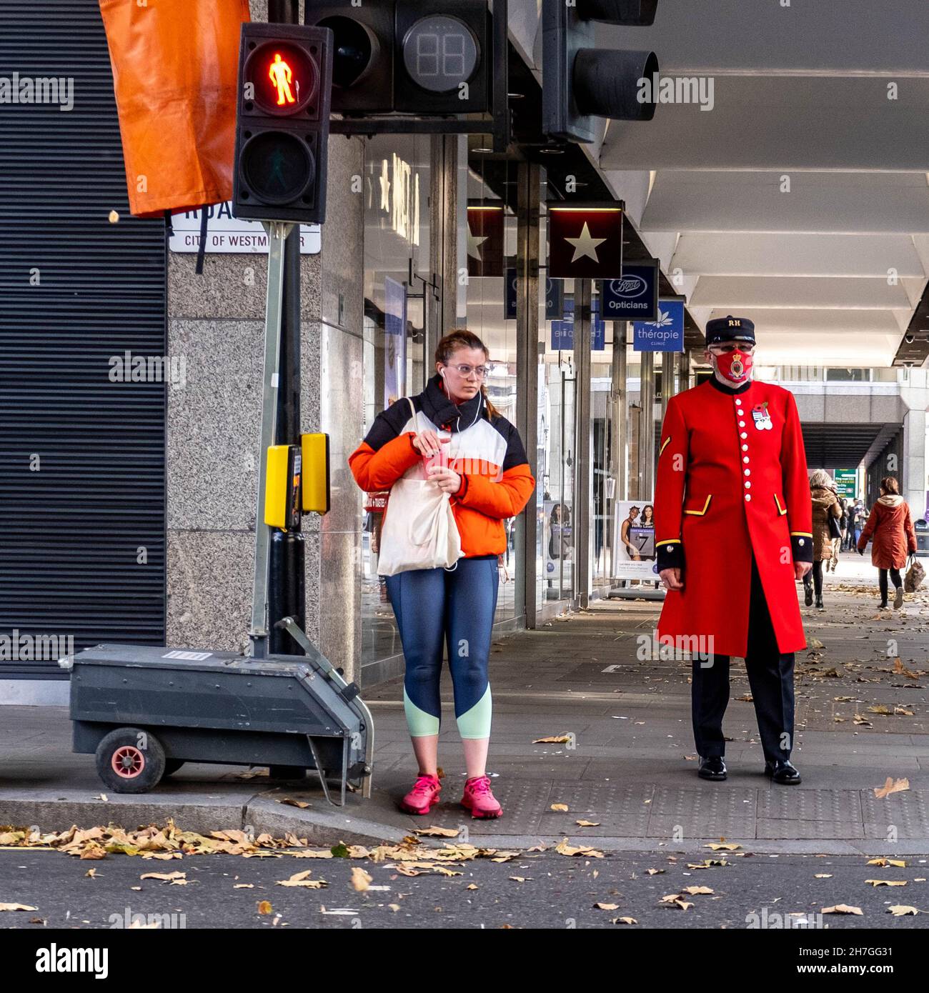 Victoria Westminster London England Großbritannien, November 7 2021, Chelsea Rentner trägt rote oder scharlachrote Uniform und schützen Gesichtsmaske wartet auf die Cross The R Stockfoto