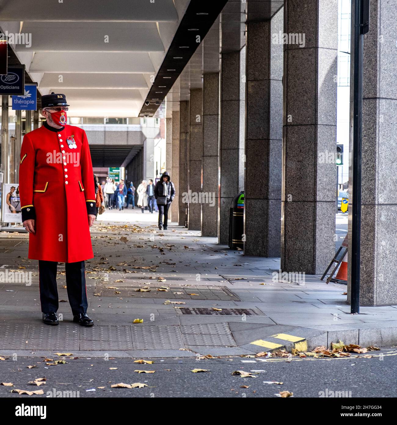Victoria Westminster London England Großbritannien, November 7 2021, Chelsea Rentner trägt rote oder scharlachrote Uniform und schützen Gesichtsmaske wartet auf die Cross The R Stockfoto