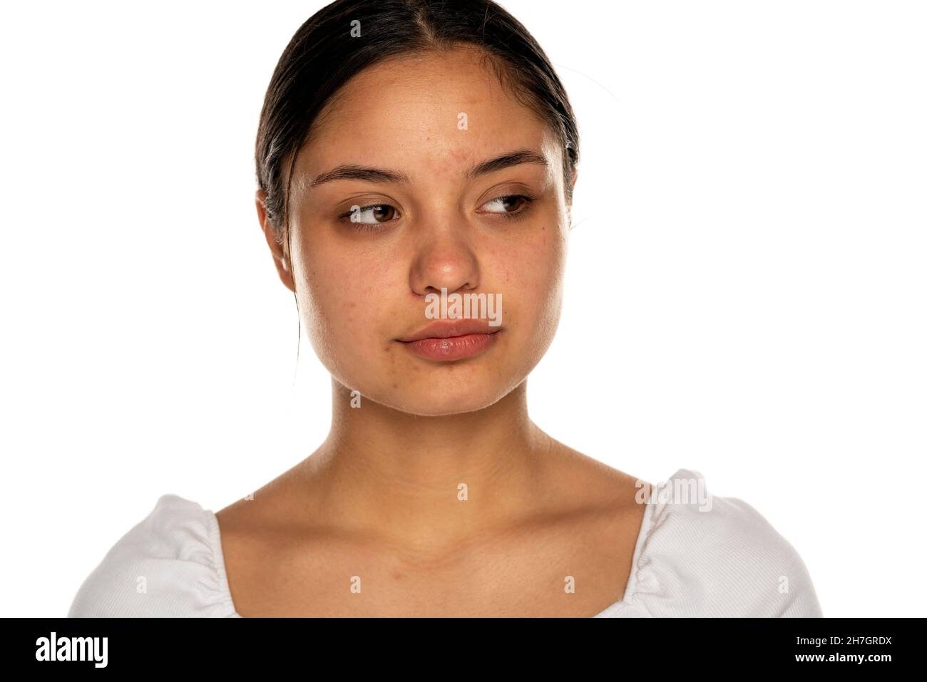 Eine junge Frau ohne Make-up schaut auf einen weißen Hintergrund Stockfoto