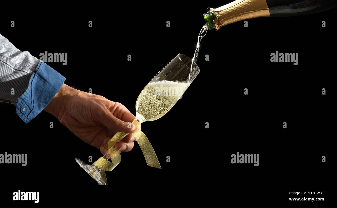 Handhaltend Weinglas mit goldenem Bogen, das aus einer glitzernden Weißweinflasche mit isoliertem Hintergrund gefüllt wird. Vorderansicht Stockfoto