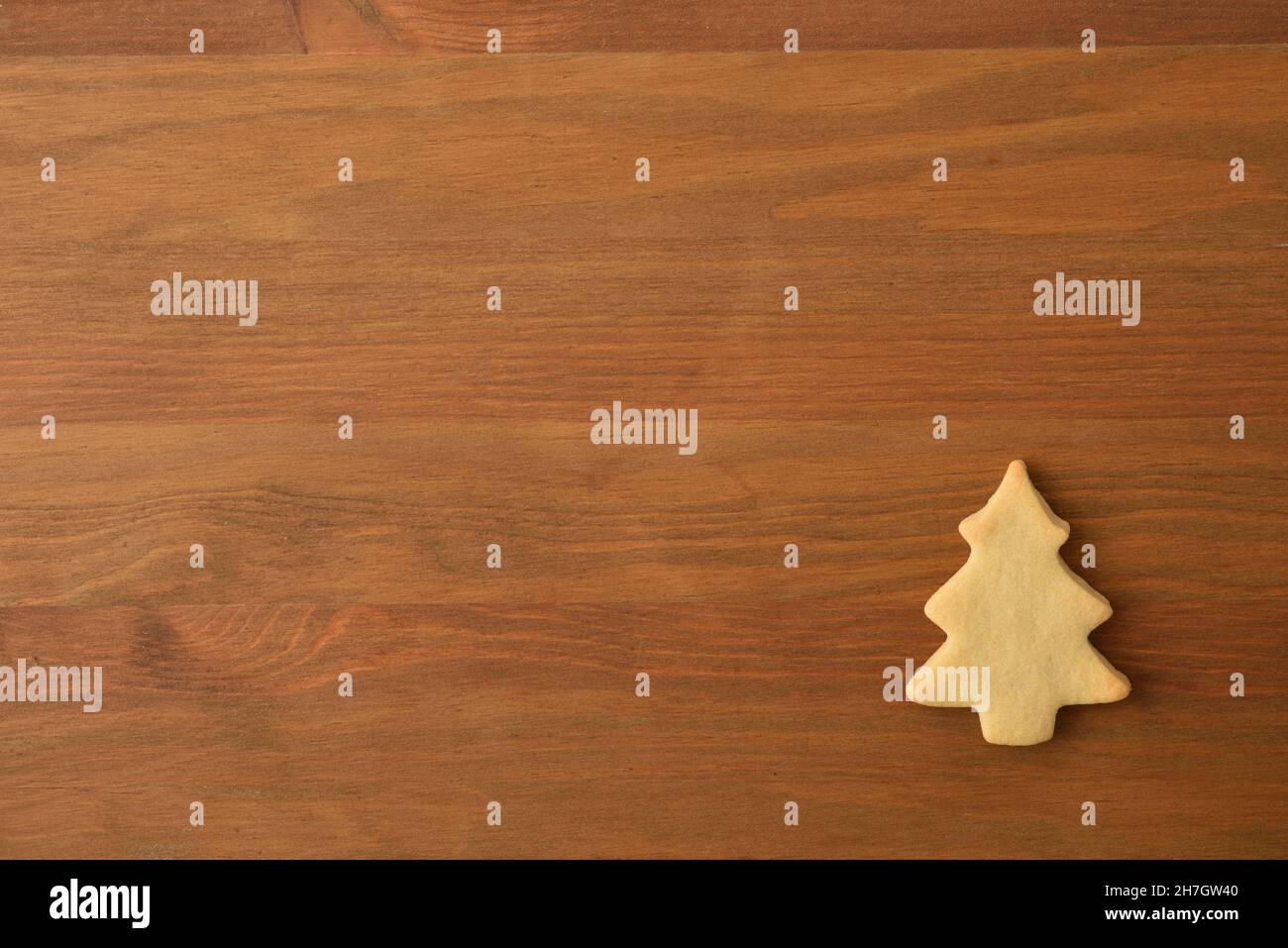 Weihnachtlicher Hintergrund mit tannenförmigem Keks in einer Ecke auf Holzhintergrund. Draufsicht. Horizontale Zusammensetzung. Stockfoto