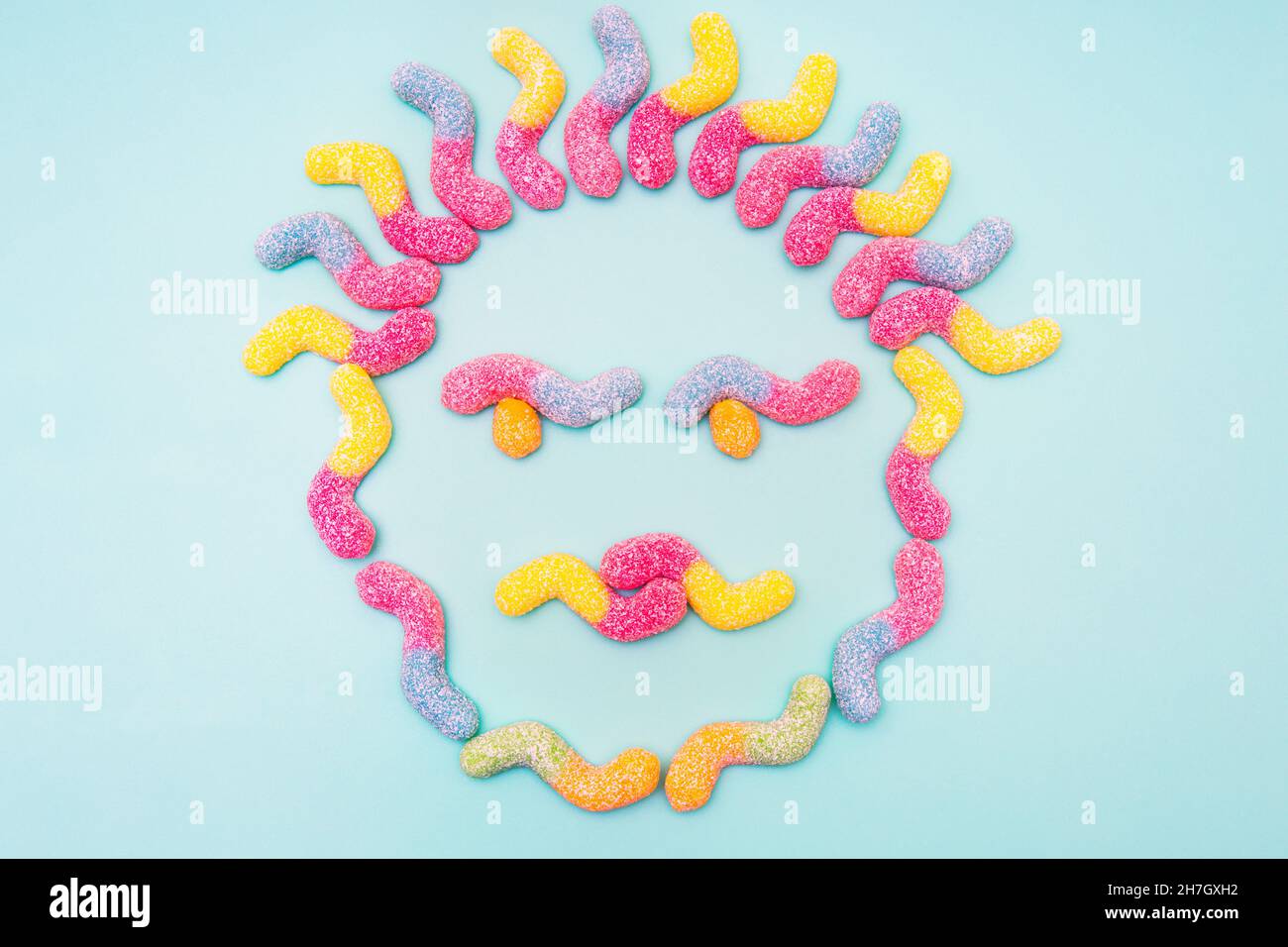 Gesicht aus zuckerbeschichteten Gummiwürmern auf blauem Hintergrund isoliert Stockfoto