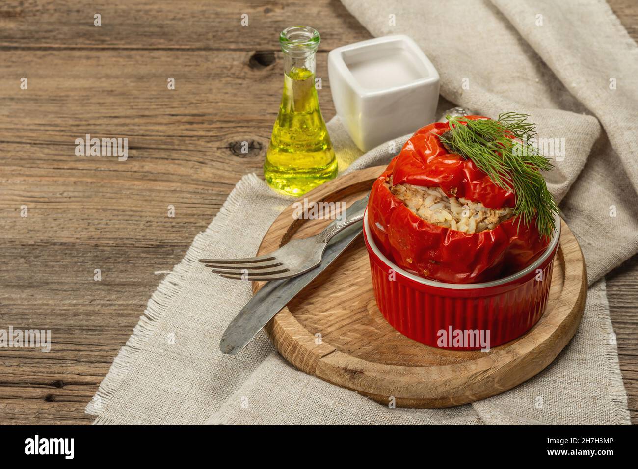 Hausgemachtes Fleisch und Reis gefüllte Paprika. Olivenöl, Sauce, Besteck. Traditionelles gesundes Essen, Vintage-Holzhintergrund, Kopierraum Stockfoto