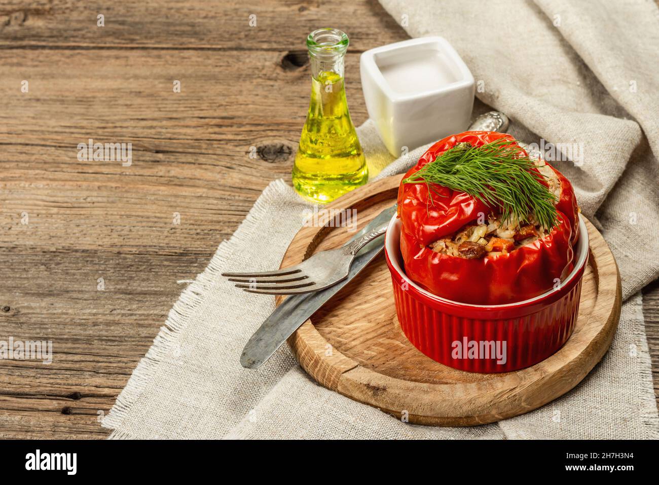 Hausgemachtes Fleisch und Reis gefüllte Paprika. Olivenöl, Sauce, Besteck. Traditionelles gesundes Essen, Vintage-Holzhintergrund, Kopierraum Stockfoto