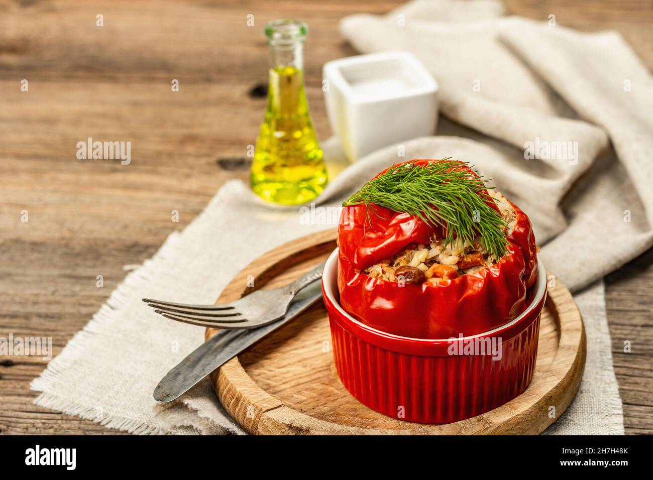 Hausgemachtes Fleisch und Reis gefüllte Paprika. Olivenöl, Sauce, Besteck. Traditionelles gesundes Essen, Vintage-Holzhintergrund, Kopierraum Stockfoto