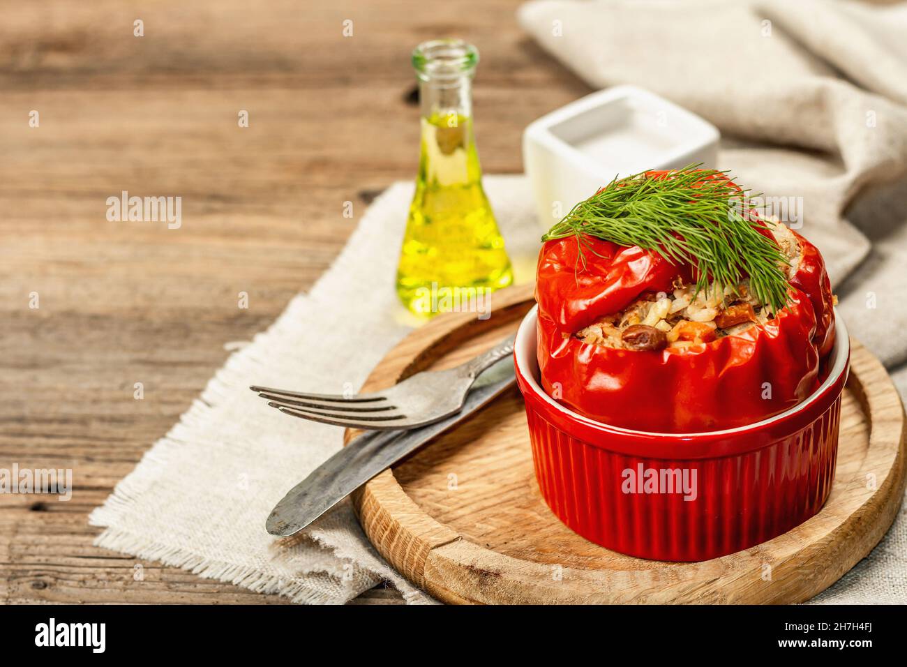 Hausgemachtes Fleisch und Reis gefüllte Paprika. Olivenöl, Sauce, Besteck. Traditionelles gesundes Essen, Vintage-Holzhintergrund, Kopierraum Stockfoto