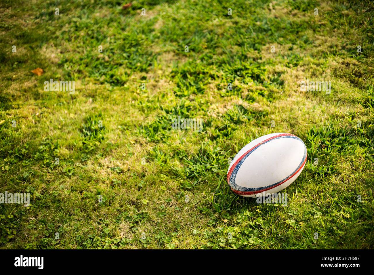 Rugby Ball, Gilbert, auf Sportplatz mit grünem Gras für das Spiel Rugby. Konzentrieren Sie sich auf den Ball, die Sportbasis im Hintergrund. Stockfoto
