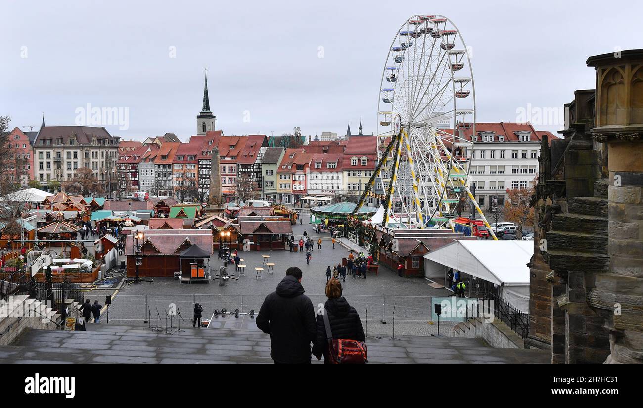 Erfurt, Deutschland. 23rd. November 2021. Besucher spazieren durch den Erfurter Weihnachtsmarkt. Die meisten thüringischen Städte haben ihre Weihnachtsmärkte aufgrund der besorgniserregenden Infektionszahlen gestrichen. Nun steht eine Verschärfung der Corona-Maßnahmen in den Angen. Am 24. November wird der landtag über weitere Einschränkungen diskutieren. Daher ist derzeit unklar, ob die Weihnachtsmärkte bis Ende Dezember geöffnet bleiben dürfen. Quelle: Martin Schutt/dpa-Zentralbild/dpa/Alamy Live News Stockfoto