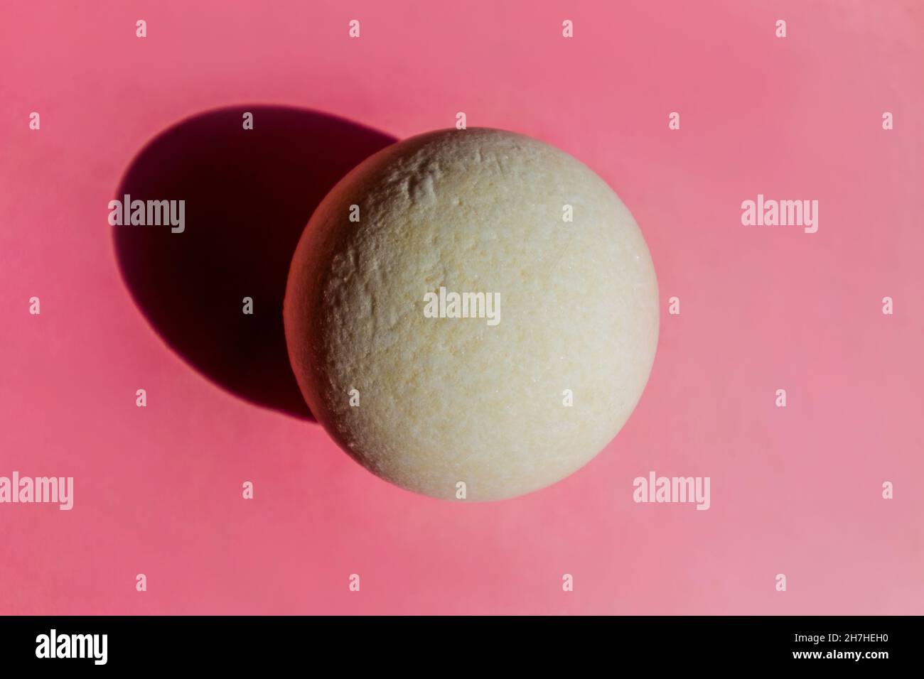 Weiße runde Badebombe auf rosa Hintergrund. Badezimmerzubehör. Stockfoto