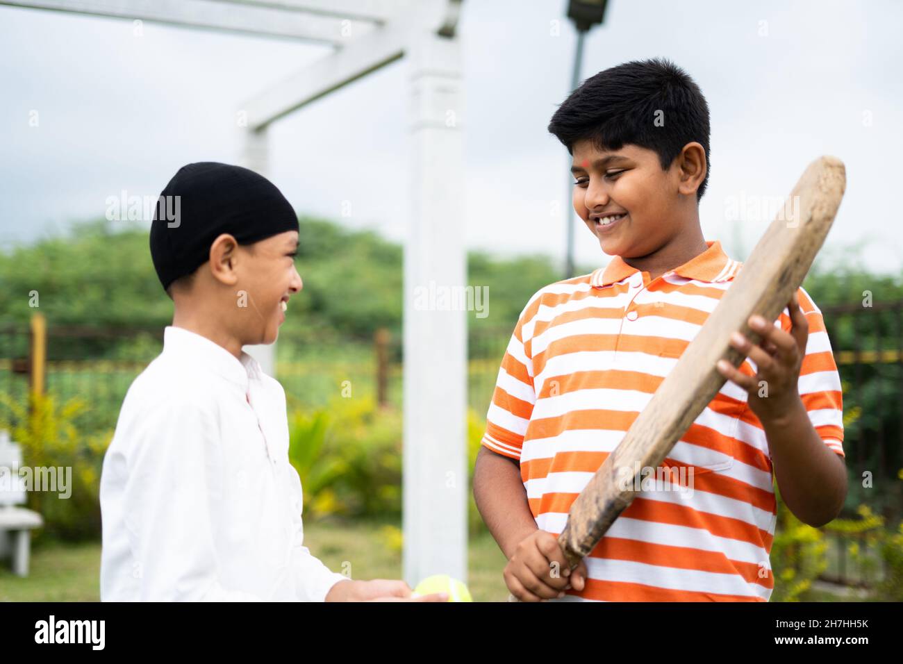 Glückliche indische multiethnische Kinder mit Schläger und Ball gehen Cricket spielen - Konzept der Freundschaft, Outdoor-Aktivitäten und kommunale Harmonie. Stockfoto