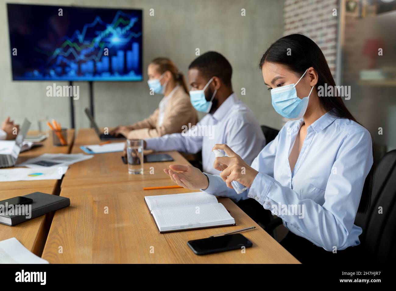 Neuer Normalwert. Asian Female In Face Mask Mit Desinfektionsmittel Spray Im Büro Stockfoto