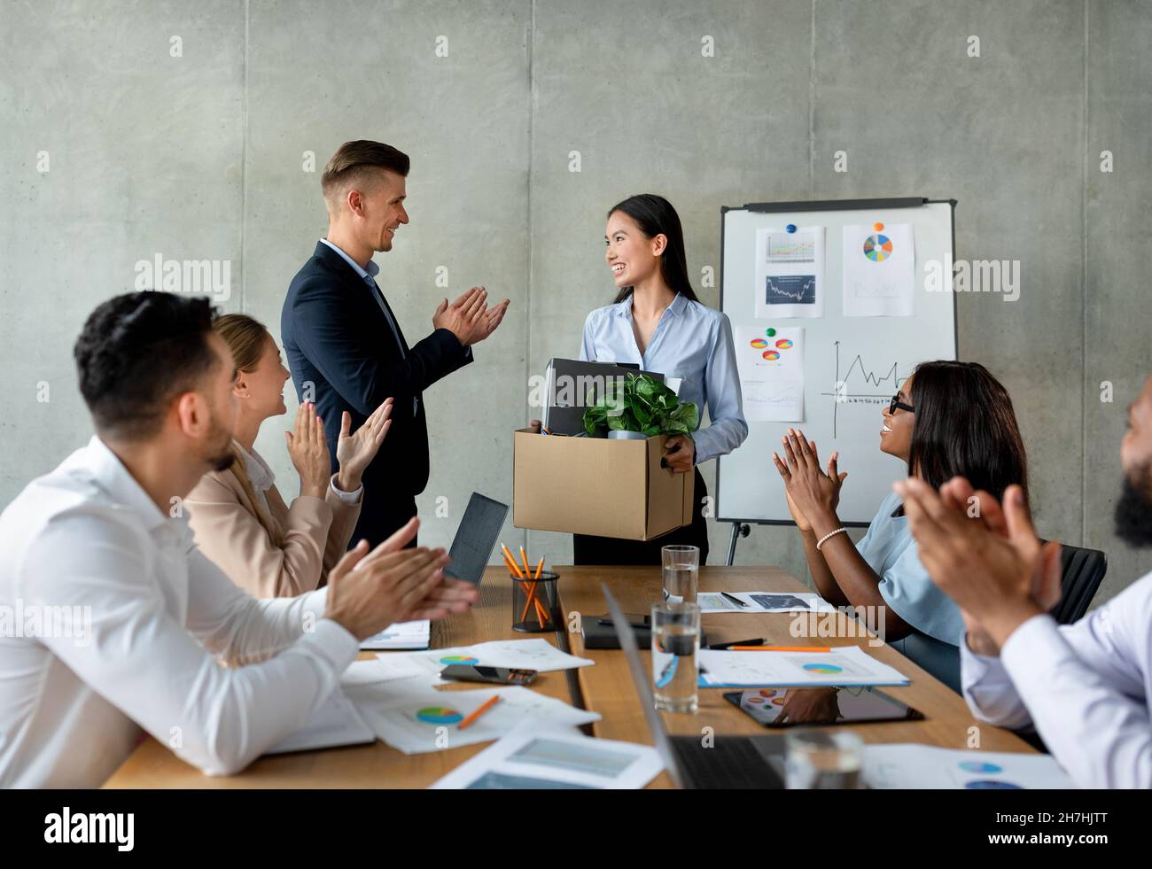 Gruppe Von Geschäftsleuten, Die Applaudieren Und Eine Asiatische Mitarbeiterin In Ihrem Team Begrüßen Stockfoto