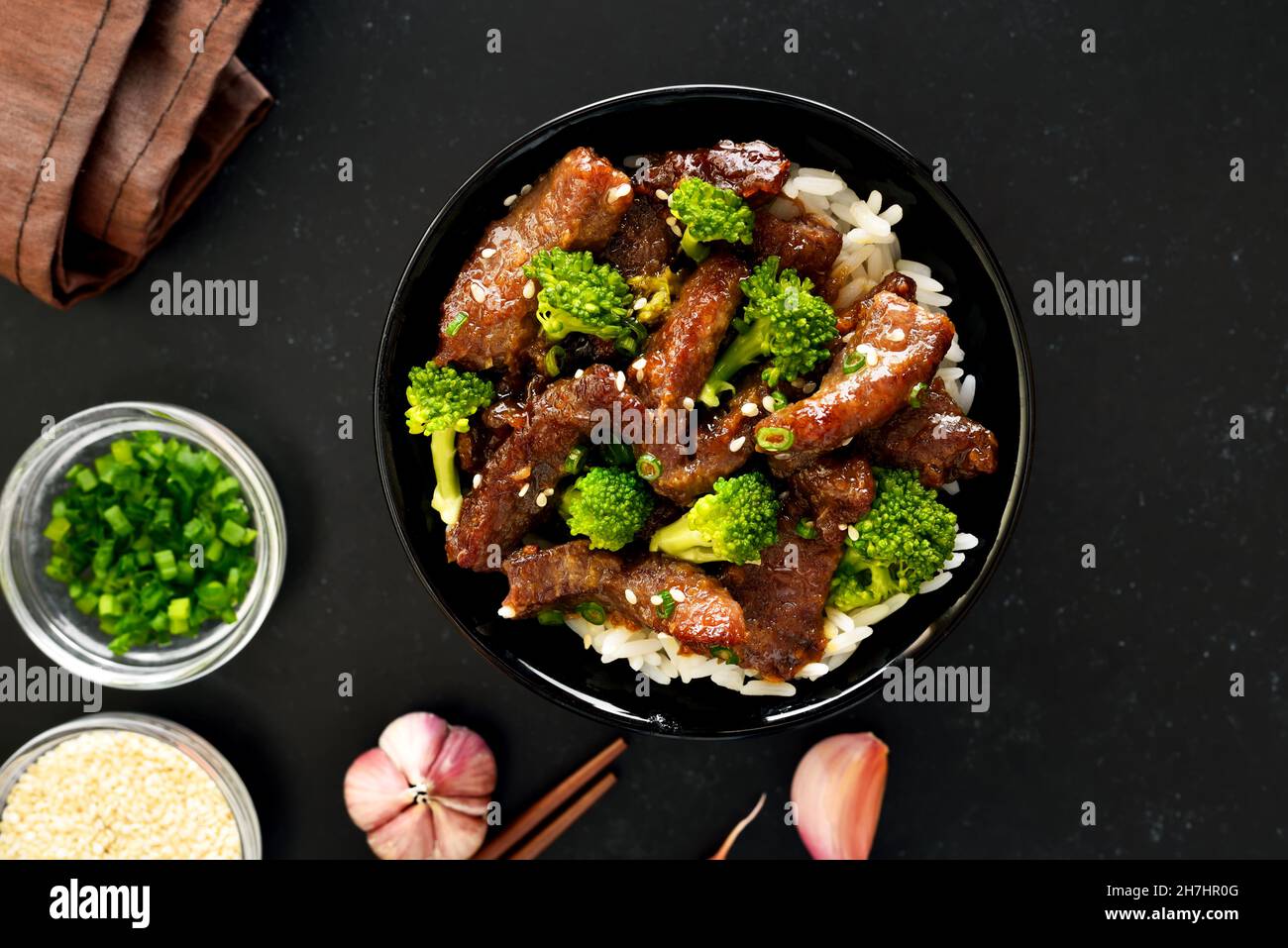 Rindfleisch und Brokkoli unter Rühren mit Reis auf dunklem Grund braten. Draufsicht, flach liegend Stockfoto