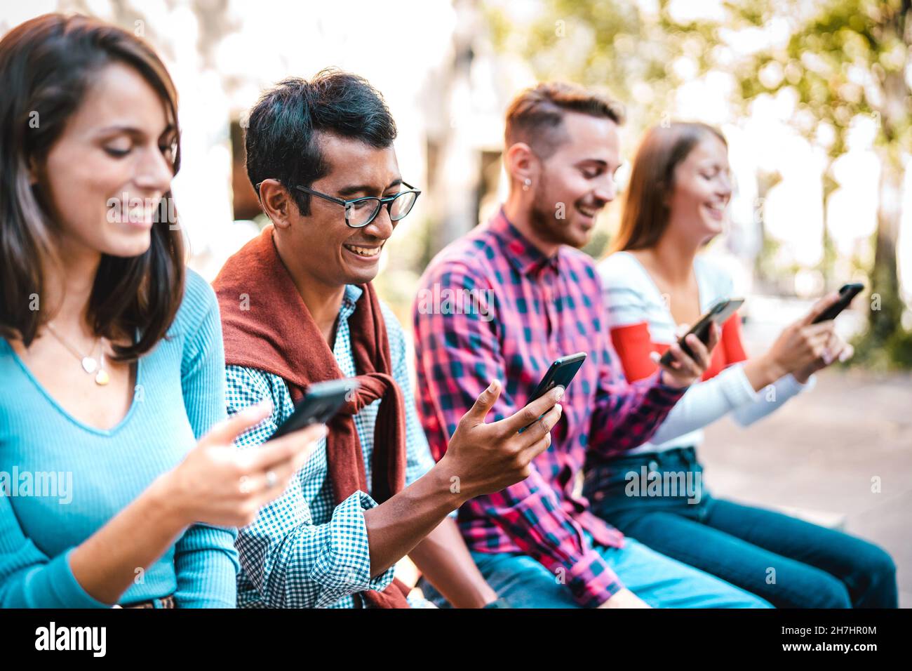 Multikulturelle Studenten lachen auf dem Universitätscampus mit dem Smartphone - Junge Leute Freunde, die vom Handy süchtig sind Stockfoto