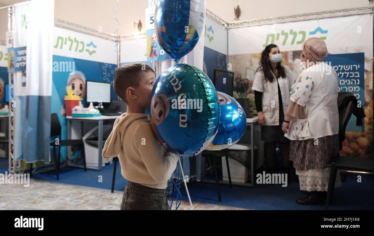 Jerusalem, Israel. 23rd. November 2021. Ein israelischer Junge hält Helium-Ballons, während er wartet, um eine Dosis des Pfizer/BioNTech Covid-19-Impfstoffs bei der Clalit Health Service Organization zu erhalten, als Israel am 21. November 2023 in Jerusalem, Israel, eine Impfkampagne gegen das Coronavirus für 5- bis 11-Jährige beginnt. Am 23. November 2021 in Jerusalem, Israel. Menschen ab 12 Jahren in Israel haben bereits Anspruch auf den zweidosigen Pfizer-BioNTech-Impfstoff und einen Follow-up-Booster. Kredit: Eddie Gerald/Alamy Live Nachrichten Stockfoto