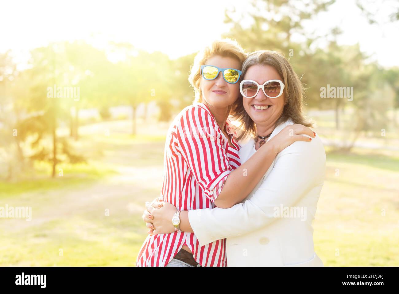 Porträt zweier kaukasischer Frauen mittleren Alters, die ihre Freundschaft feiern und sich umarmen und lächeln. Stockfoto