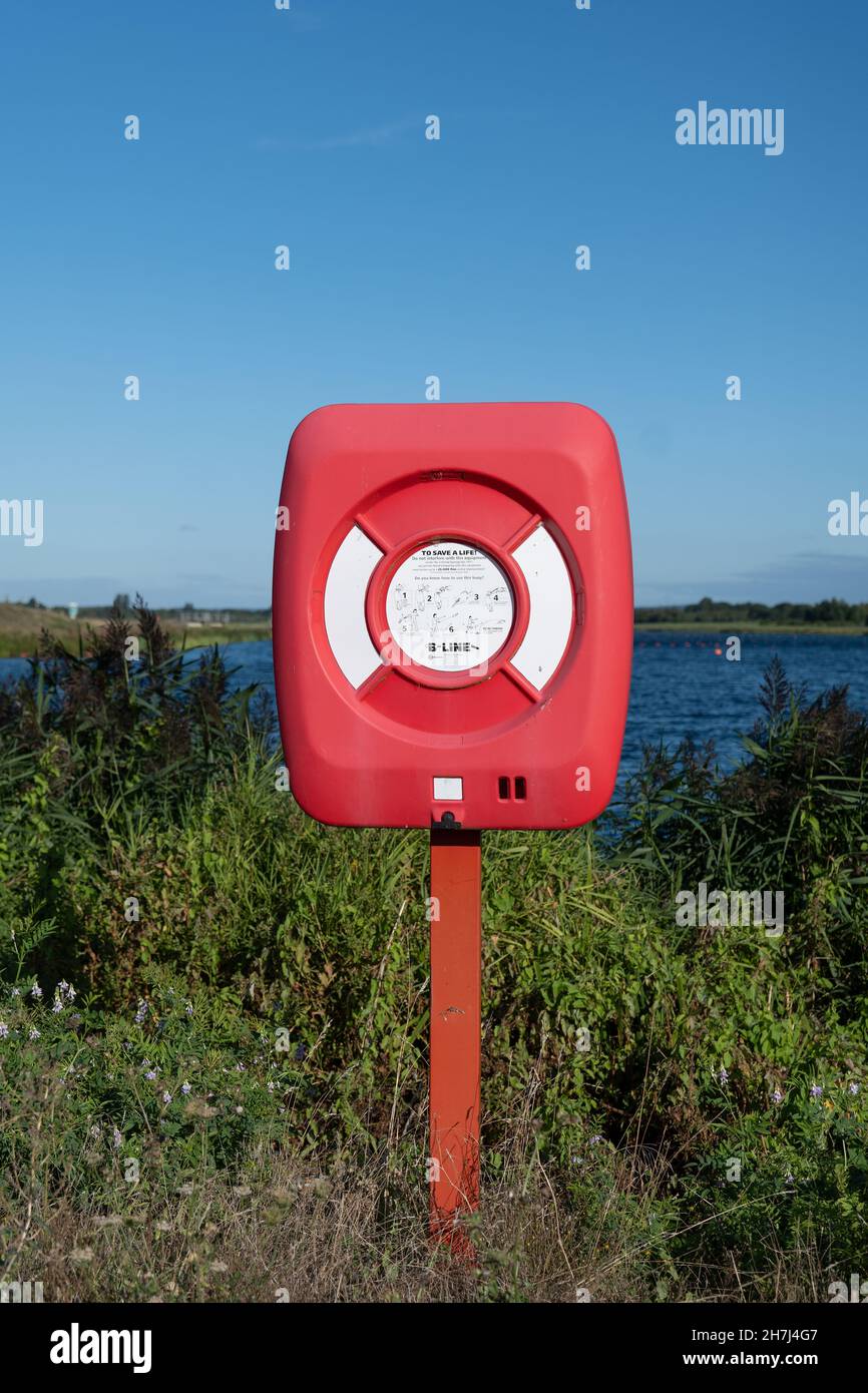 Eine Rettungsboje in einem roten Fall auf einem roten Pfosten - verwendet, um Menschen im Notfall auf dem Wasser zu retten - am Dorney Lake im Vereinigten Königreich. Stockfoto