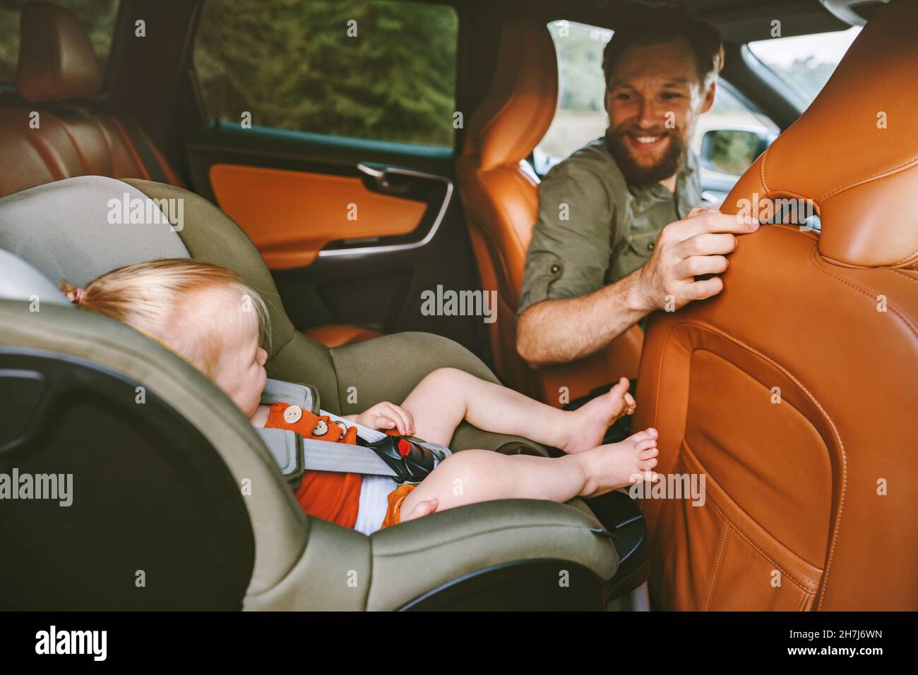 Kind im Auto sitzt in einem Sicherheitssitz Familie unterwegs Vater Mann Fahrer Familie Urlaub mit Baby Reise Lifestyle Kinder Taxi Transfer Stockfoto