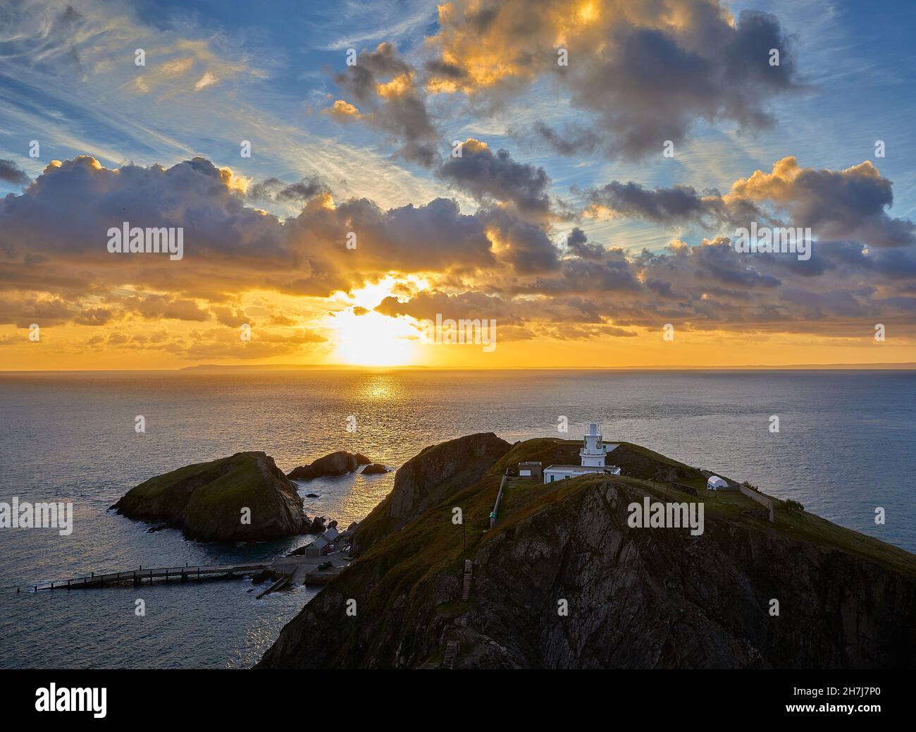 Sonnenaufgang über Süden Licht Leuchtturm und die oldenberg Landung Jetty aus Mariscos" Schloss auf der Insel Lundy vor der Küste von Devon, Großbritannien Stockfoto