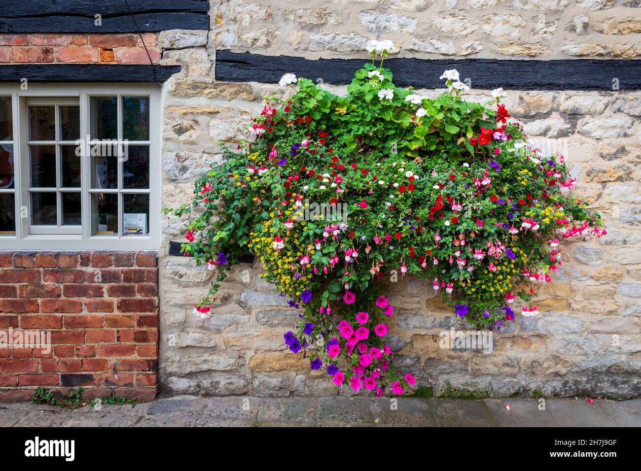 Ein farbenfroher Hängekorb in einer Seitenstraße von Helmsley, North York Moors National Park, Yorkshire, England Stockfoto