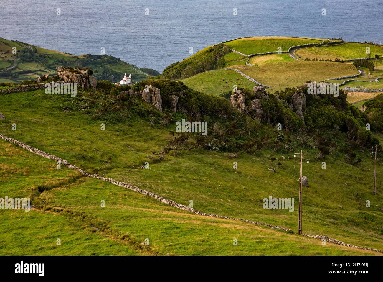 Eine weiße Kirche ist malerisch eingerahmt von einer saftig grünen Hügellandschaft auf den Azoren Stockfoto