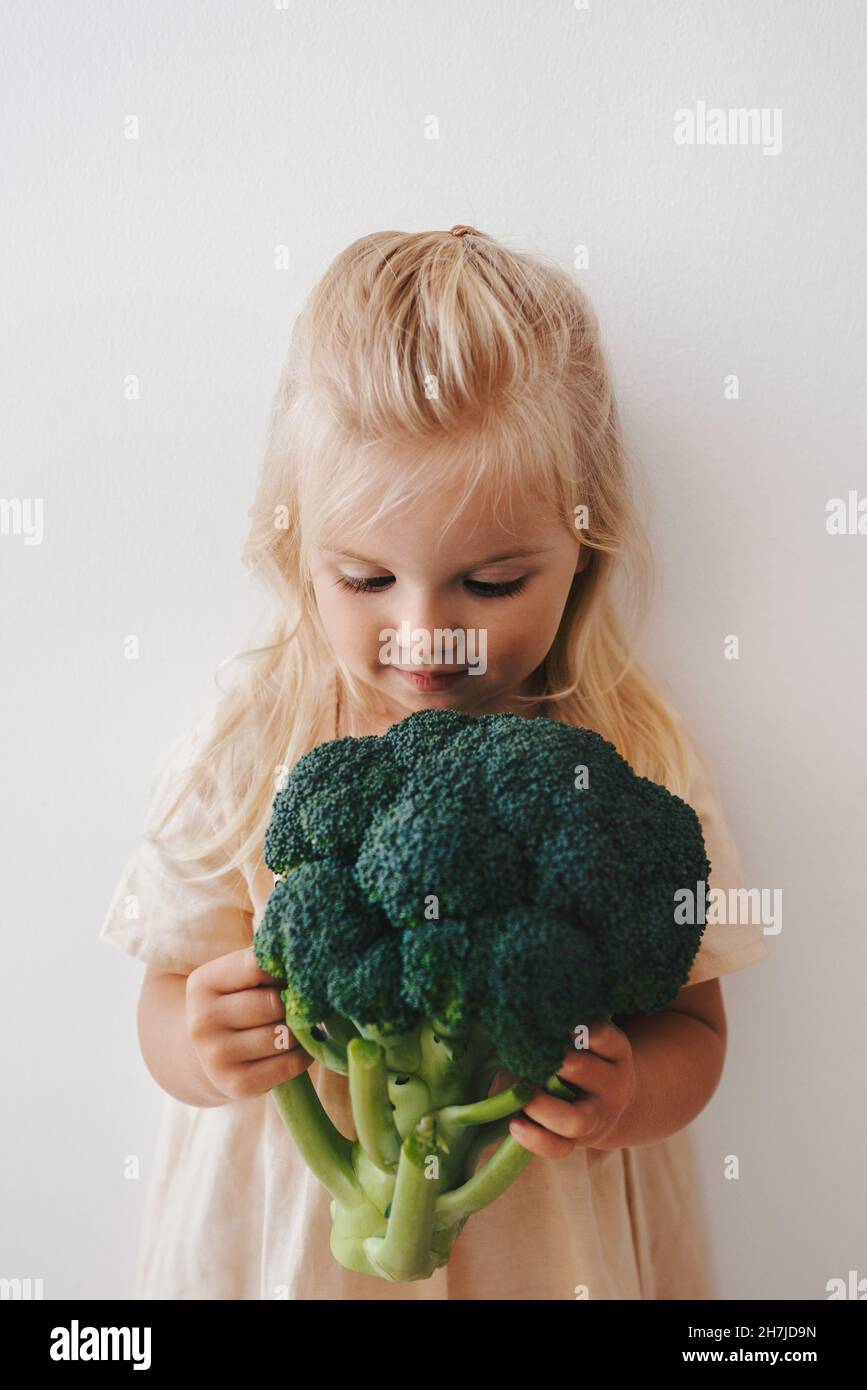 Kind mit Brokkoli Gemüse gesunde Ernährung vegan Lifestyle organisch selbstgewachsenes Gemüse pflanzenbasierte Ernährung Mädchen Kind Kochen Stockfoto