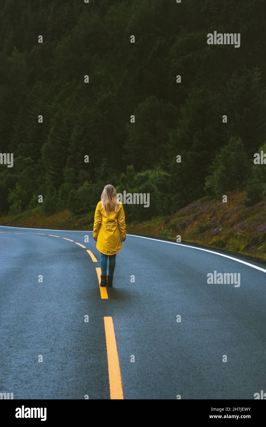 Entfliehen Sie alles Frau auf der Straße im Wald allein reisen Freiheit Konzept Urlaub im Freien in Norwegen Mädchen trägt gelben Regenmantel auf dem Weg Stockfoto