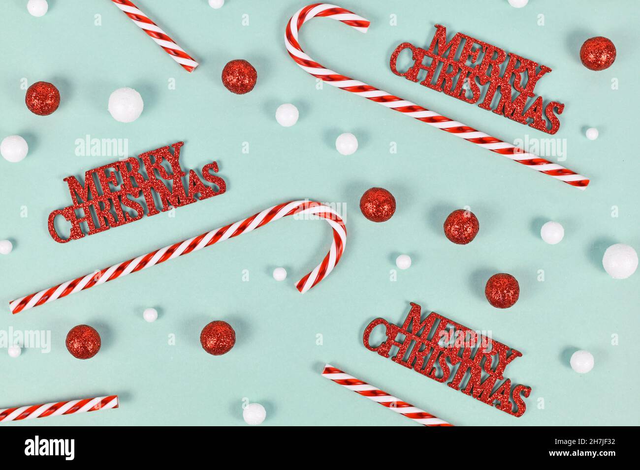 Weihnachtsschmuck mit „Merry Christmas“-Text, Zuckerstöcken und Schneebällen auf mintgrünem Hintergrund Stockfoto