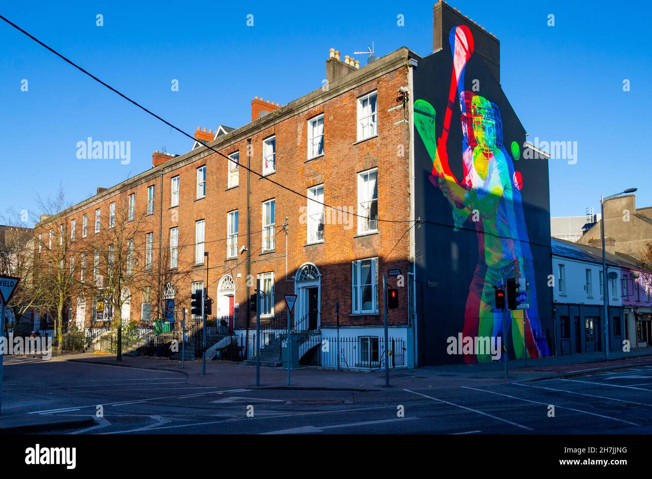 Reihe von Reihenhäusern in Cork City Ireland mit Wandbild eines Mannes, der auf einen Giebelkiebel schleudert Stockfoto