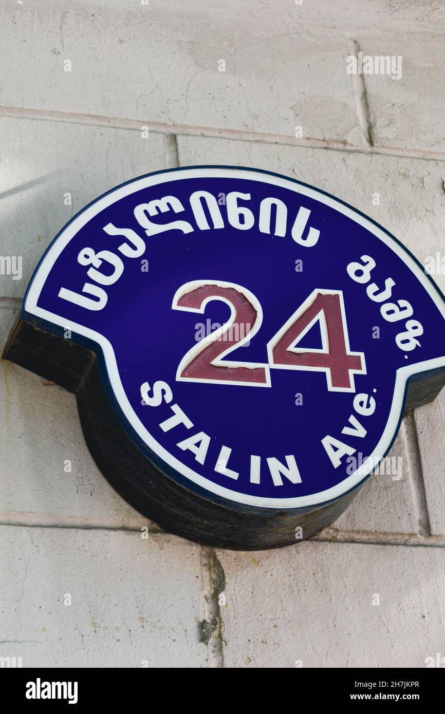 Schild mit Straßennamen in georgischer und englischer Sprache auf dem Gebäude der georgischen Stadt Gori sagen Stalin Avenue. Gori ist der Geburtsort von Stockfoto