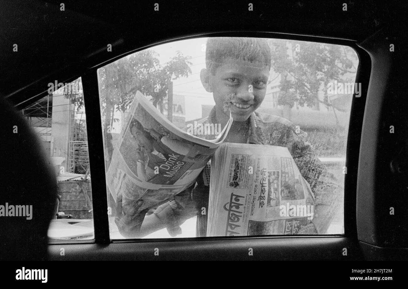 Ein kleiner Junge verkauft Zeitungen am Kreisverkehr in Moghbazar in Dhaka, der Hauptstadt von Bangladesch. Stockfoto