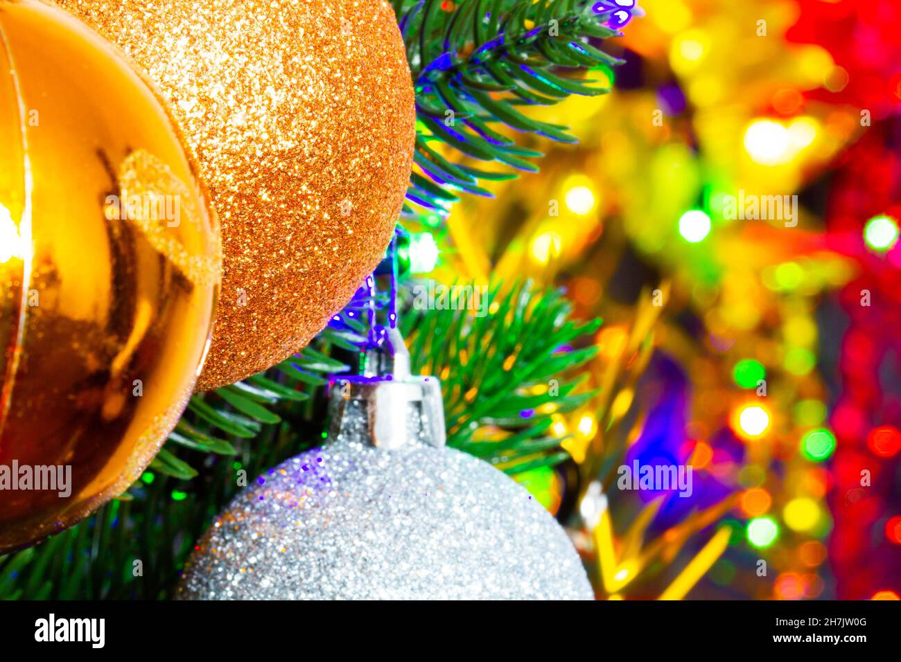 Weihnachtsspielzeug auf dem Weihnachtsbaum auf dem bunten Lichthintergrund. Wunderschöne Weihnachtsdekorationen aus Glas. Coole helle Neujahrsspielzeuge Stockfoto