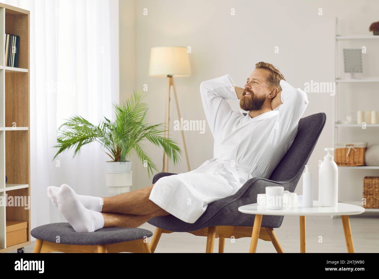Porträt eines bärtig lächelnden Mannes im Bademantel, der sich entspannt und seine Freizeit genießt. Stockfoto