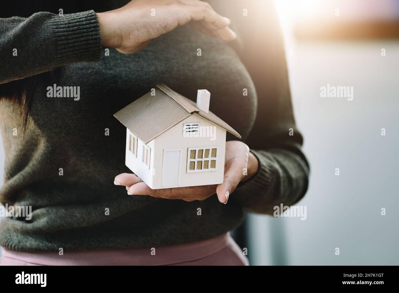 Immobilienmakler gesturing, um Häuser zu schützen, Wohnungsversicherung Konzept. Stockfoto