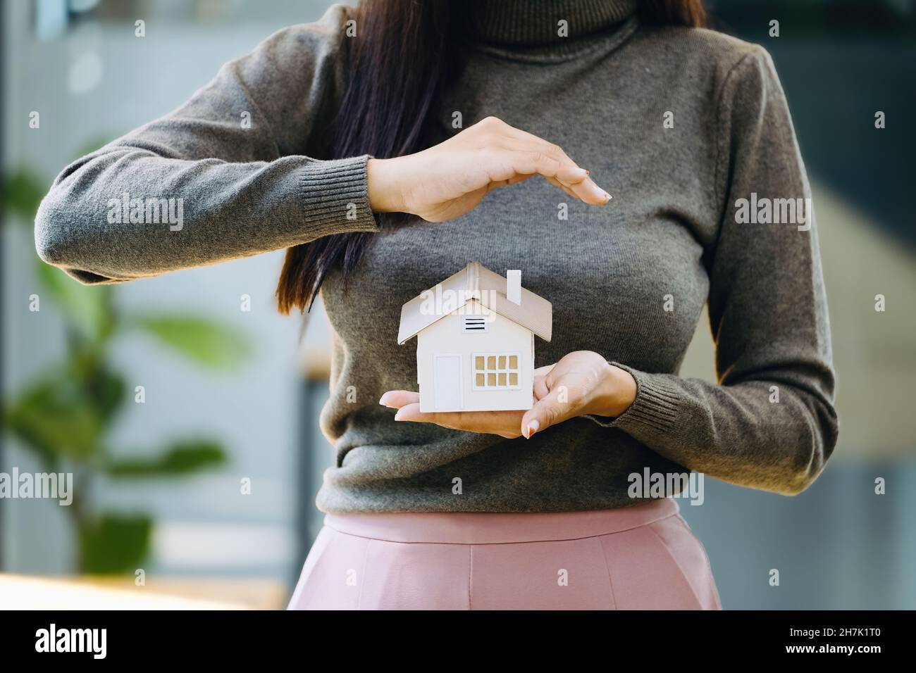 Immobilienmakler gesturing, um Häuser zu schützen, Wohnungsversicherung Konzept. Stockfoto