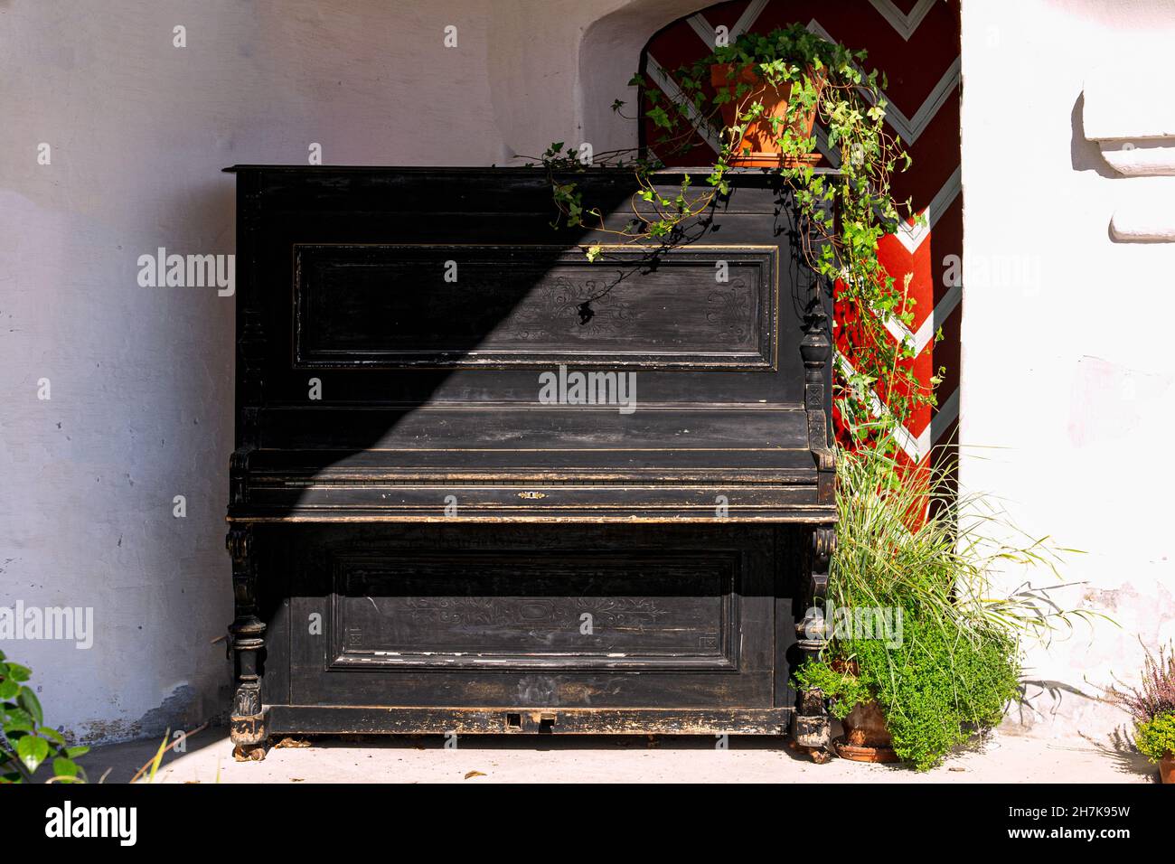 Ein altes schwarzes Klavier in einem Landhaus in der Ecke der Terrasse. Stockfoto
