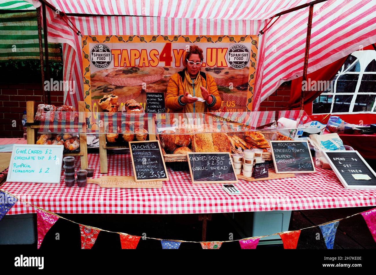 Eine Frau halter Abschaltdruck am ist ein Britischer Landwirt Markt mit einer Auswahl an spanischen Tapas essen Stockfoto
