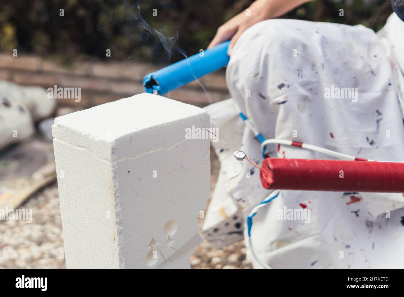 Frau schneidet einen Block aus Polystyrol mit einem heißen Stahlkabel im Freien Stockfoto