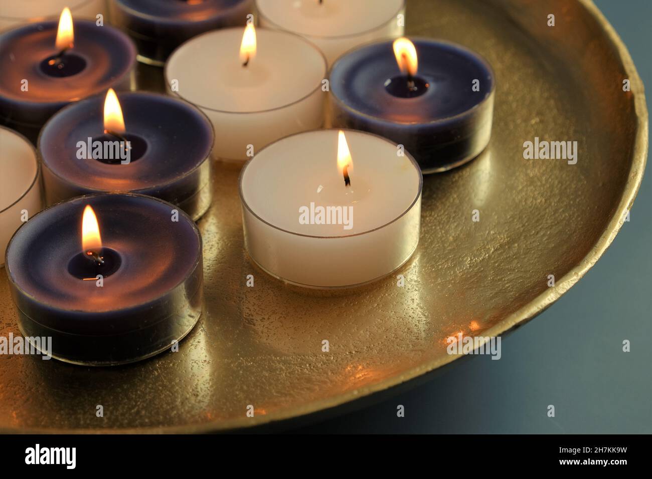Kerzenflamme. Brennende Kerzen in einem goldenen Tablett auf einem dunkelblauen Hintergrund.Kerzen Hintergrund. Stockfoto