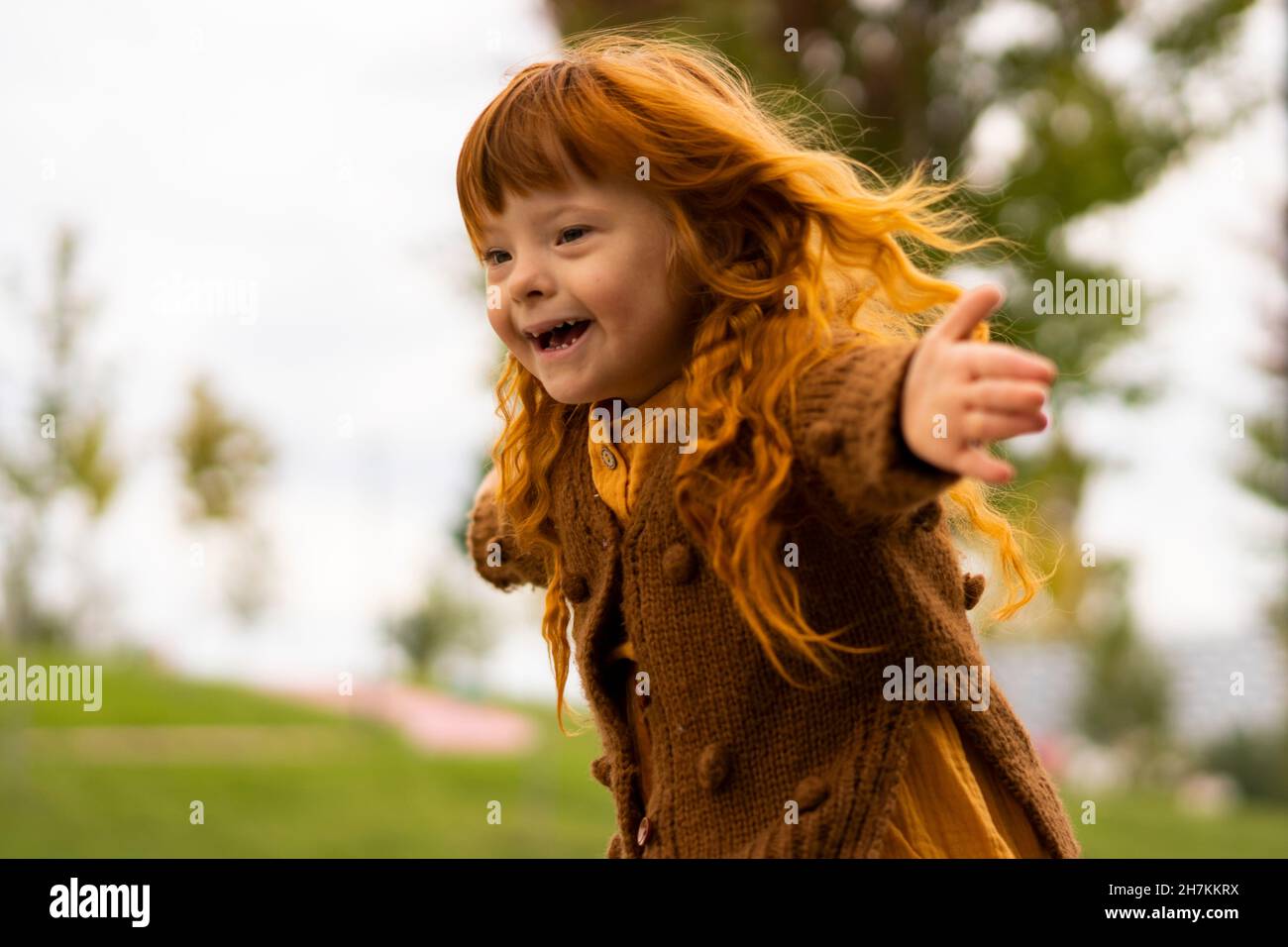 Fröhliches Mädchen mit Down-Syndrom läuft im Park Stockfoto